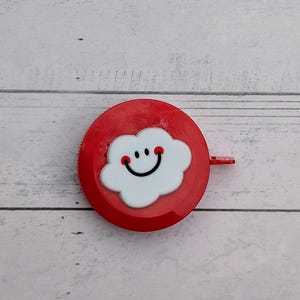 Puede incluir: Un bot&oacute;n redondo rojo con una nube blanca con una cara sonriente.