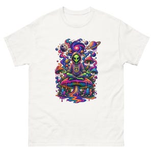 May include: A white t-shirt featuring a colourful graphic of a green alien in a hoodie sitting in a meditative pose on a large mushroom. The design includes swirling cosmic patterns, planets, smaller mushrooms, and crystals in vibrant hues.
