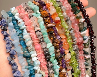 May include: A collection of chip gemstone strands in various colors, including blue, green, pink, brown, and purple. The strands are made of small, irregular chips of gemstone, and they are arranged in a loose, flowing style.