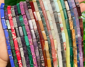 May include: A collection of colorful, rectangular gemstone beads. The beads are made of various types of stones, including malachite, amethyst, jasper, and agate. The beads are arranged in rows, with each row featuring a different type of stone.