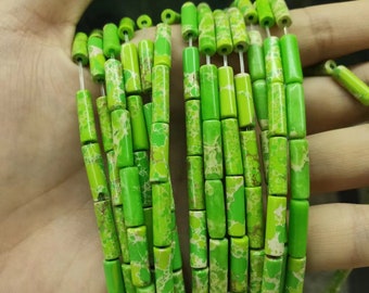 May include: A strand of green and white patterned cylindrical beads. The beads are strung on a clear thread and are approximately 1/2 inch in length.