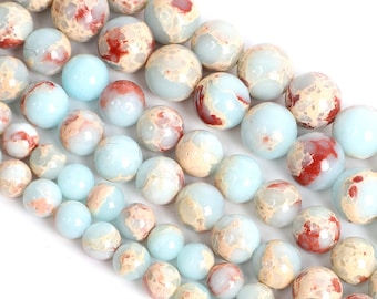 May include: Strands of round gemstone beads in varying sizes. The beads feature a mix of colors, including light blue, beige, and red-brown. The beads are smooth and appear to be polished, suitable for jewelry making.