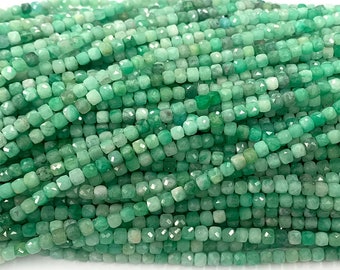May include: A strand of green gemstone beads, each bead is faceted and has a square shape.