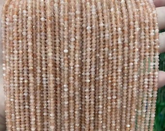May include: A strand of peach-colored sunstone beads. The beads are faceted and have a shimmery, iridescent finish. The beads are strung on a clear thread and are approximately 2mm in diameter.