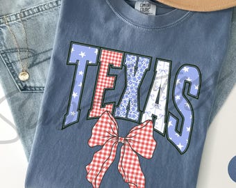 May include: A blue jean shirt with a red, white, and blue patchwork design that says "TEXAS" with a red and white gingham bow.