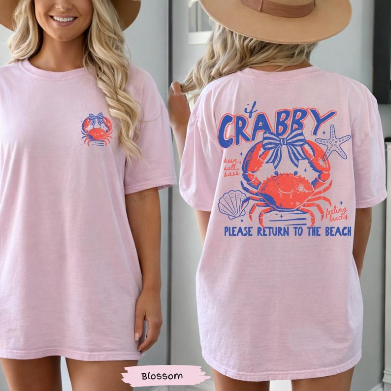Puede incluir: Camiseta rosa claro con un dise&ntilde;o de cangrejo en la parte delantera y trasera. La parte delantera presenta un peque&ntilde;o dise&ntilde;o de cangrejo, mientras que la parte trasera muestra un cangrejo m&aacute;s grande con el texto "If Crabby, Please Return to the Beach". Prenda informal con tem&aacute;tica playera.