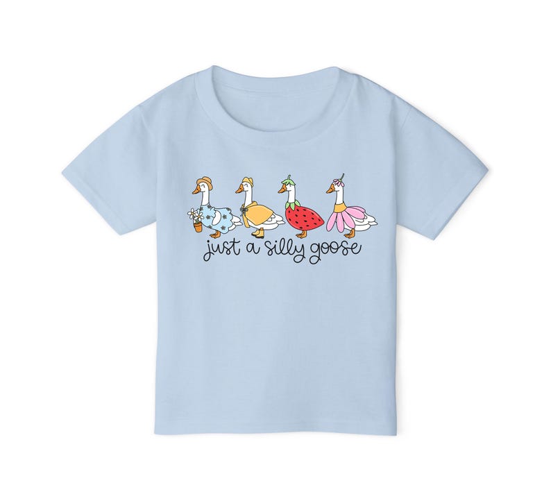 以下が含まれることがあります： 薄い青色のTシャツに、異なるコスチュームを着た4羽のガチョウのグラフィックがプリントされています。ガチョウの下には「just a silly goose」というテキストがプリントされています。