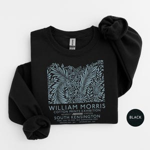 Puede incluir: Sudadera negra de cuello redondo con un dise&ntilde;o floral en tonos azules y grises. El dise&ntilde;o incluye el texto "WILLIAM MORRIS COTTON PRINTS EXHIBITION" y otros detalles. Una sudadera de estilo cl&aacute;sico.