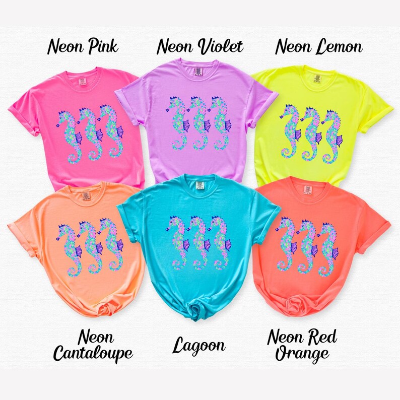 May include: Six colorful t-shirts in neon shades of pink, violet, lemon, cantaloupe, lagoon, and red-orange. Each shirt features a seahorse design in shades of blue, purple, and green. The names of the colors are printed above the shirts.