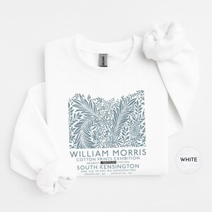 Puede incluir: Sudadera blanca con un dise&ntilde;o floral azul y el texto "WILLIAM MORRIS COTTON PRINTS EXHIBITION" que detalla el evento de South Kensington. La prenda est&aacute; hecha de un material suave, ideal para el uso diario.