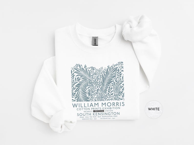Puede incluir: Sudadera blanca con un dise&ntilde;o floral azul y el texto "WILLIAM MORRIS COTTON PRINTS EXHIBITION" que detalla el evento de South Kensington. La prenda est&aacute; hecha de un material suave, ideal para el uso diario.