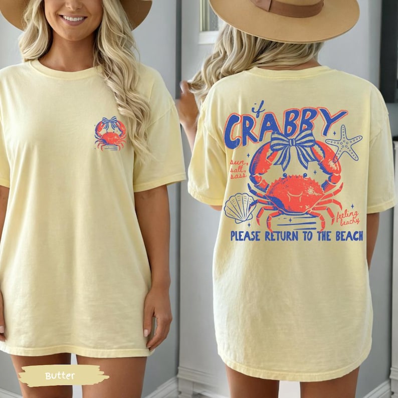 Puede incluir: Camiseta de color mantequilla con un dise&ntilde;o de cangrejo en la parte delantera y trasera. La parte trasera presenta la frase "If Crabby" sobre una ilustraci&oacute;n de cangrejo, una estrella de mar y la frase "Please Return to the Beach."