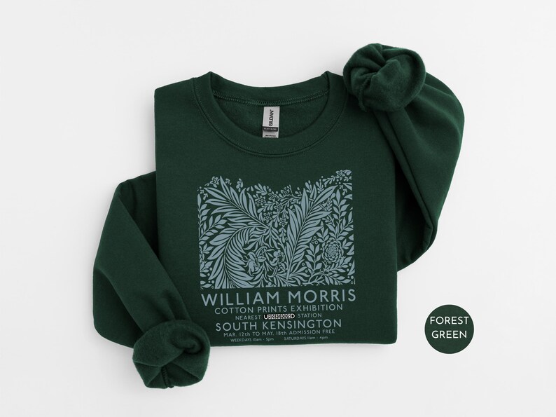 Puede incluir: Sudadera verde bosque con un dise&ntilde;o floral y texto de la exposici&oacute;n William Morris Cotton Prints. El texto incluye la ubicaci&oacute;n, South Kensington, y las fechas del 12 de marzo al 18 de mayo. La sudadera tiene mangas largas.