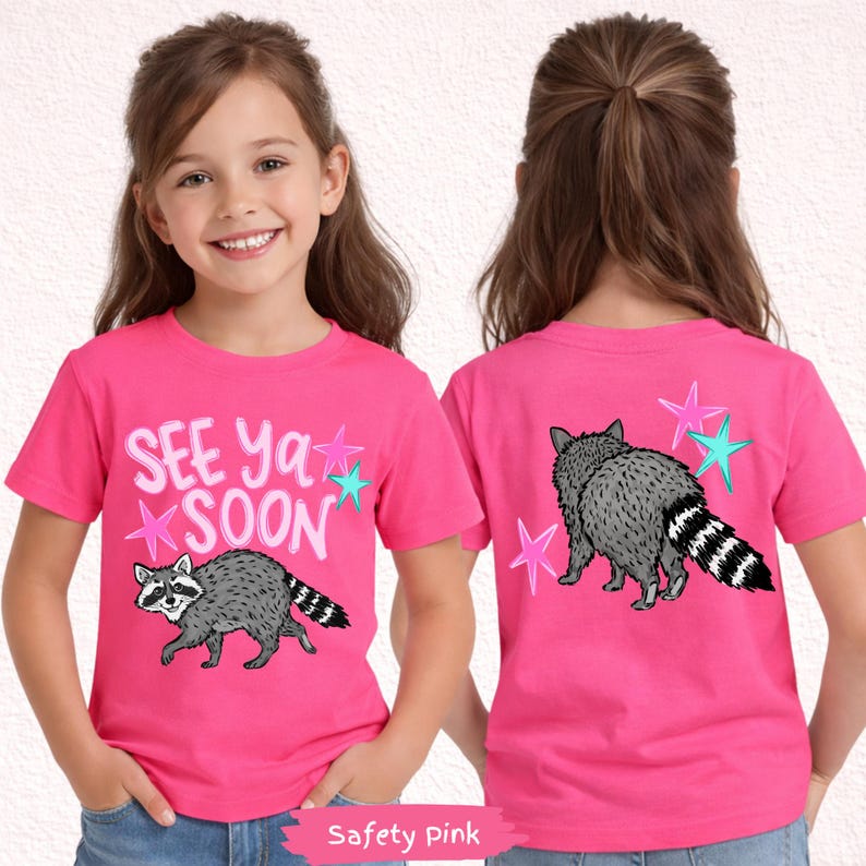May include: Safety pink t-shirt with a raccoon graphic and the text "See Ya Soon". The raccoon is gray with a black and white striped tail. Pink and teal stars surround the text and raccoon.