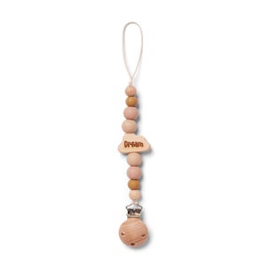 May include: A wooden pacifier clip with a string loop. The clip features a series of wooden beads in shades of pink and brown. A cloud-shaped charm with the word "Dream" is attached. The clip has a silver-colored metal clasp.