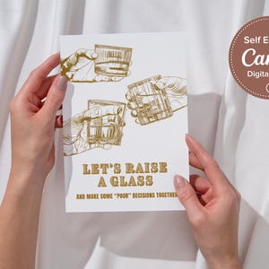 Può includere: Un biglietto bianco con lettere dorate che dice "Let's Raise a Glass and Make Some "Pour" Decisions Together". Il biglietto presenta tre illustrazioni di mani che tengono bicchieri di alcol.