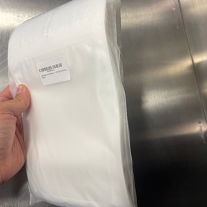 Puede incluir: Una bolsa de pl&aacute;stico blanca que contiene una pila de papel blanco apto para alimentos. La bolsa tiene una etiqueta que dice "100 bolsas por precio - 8" x 12" (20,3 x 30,5 cm)".