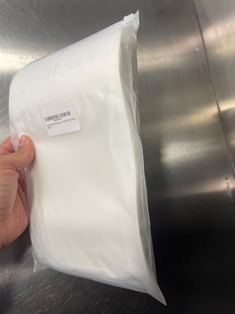 Puede incluir: Una bolsa de pl&aacute;stico blanca que contiene una pila de papel blanco apto para alimentos. La bolsa tiene una etiqueta que dice "100 bolsas por precio - 8" x 12" (20,3 x 30,5 cm)".