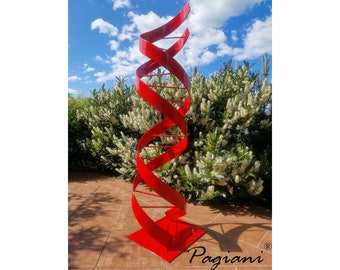 May include: A red metal sculpture in the shape of a helix, standing in a garden setting. The sculpture is made of multiple intertwined ribbons, creating a dynamic and modern design. The sculpture is signed "Pagiani" at the base.