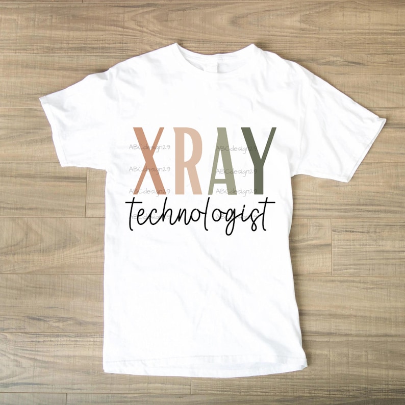 Może przedstawiać: Biała koszulka z napisem "XRAY technologist" w kolorowych literach. Litery są w odcieniach brązu, r&oacute;żu i zieleni.