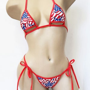 May include: Red bikini with a stars and stripes pattern. The bikini top has a triangle shape with a cut-out design. The bikini bottom has a tie-side design.