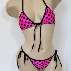 May include: A pink and black polka dot bikini with adjustable straps. The top is a triangle style and the bottom is a cheeky style.