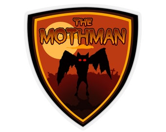 Puede incluir: Una pegatina con un diseño de escudo que muestra el texto "THE MOTHMAN" en naranja. La imagen representa una silueta negra de un Mothman con ojos rojos sobre un fondo de puesta de sol, con un cementerio al fondo.