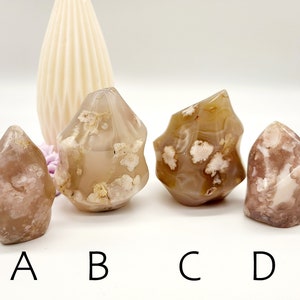 May include: Four agate crystal points in various shades of brown, pink, and white. The crystals are all freeform and have a natural, rough texture. They are labelled A, B, C, and D.