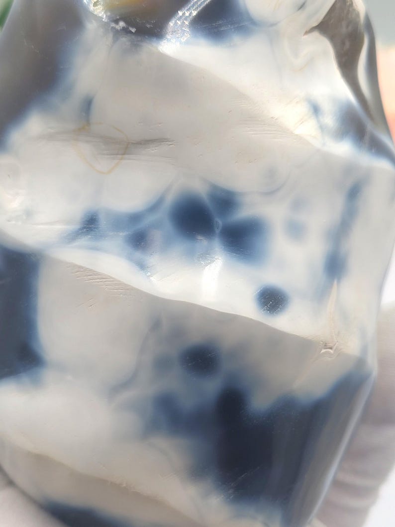 May include: A polished, irregularly shaped stone with a marbled appearance. The stone features a mix of white and deep blue hues, creating a swirling pattern. The surface is smooth and reflective, with subtle variations in color intensity.
