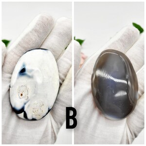 May include: Two agate stones, one white with black and gray markings, and one gray with a subtle shimmer. Both stones are smooth and oval-shaped.