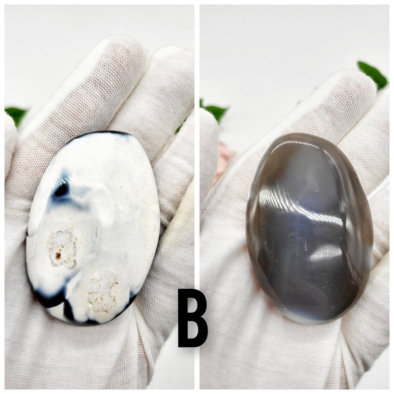 May include: Two agate stones, one white with black and gray markings, and one gray with a subtle shimmer. Both stones are smooth and oval-shaped.