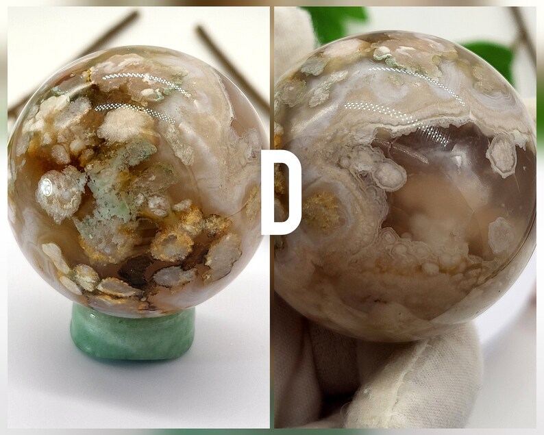 May include: A polished agate sphere with a brown, white and green pattern. The sphere is sitting on a green base.