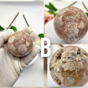 May include: A pink and white agate sphere with a unique, swirling pattern. The sphere is smooth and polished, and it has a natural, organic look.