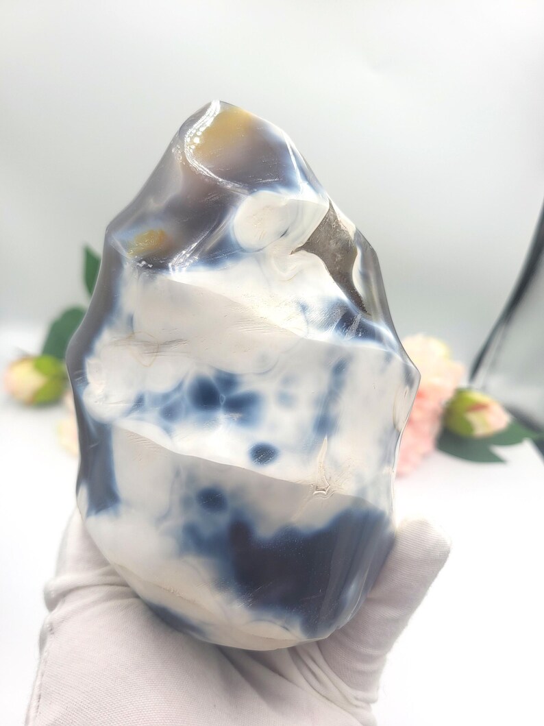 May include: A polished, freeform agate stone with a mix of white, navy blue, and tan colors. The stone has a smooth, glossy surface and a unique, organic shape. This decorative stone is ideal for home decor or as a unique gift.