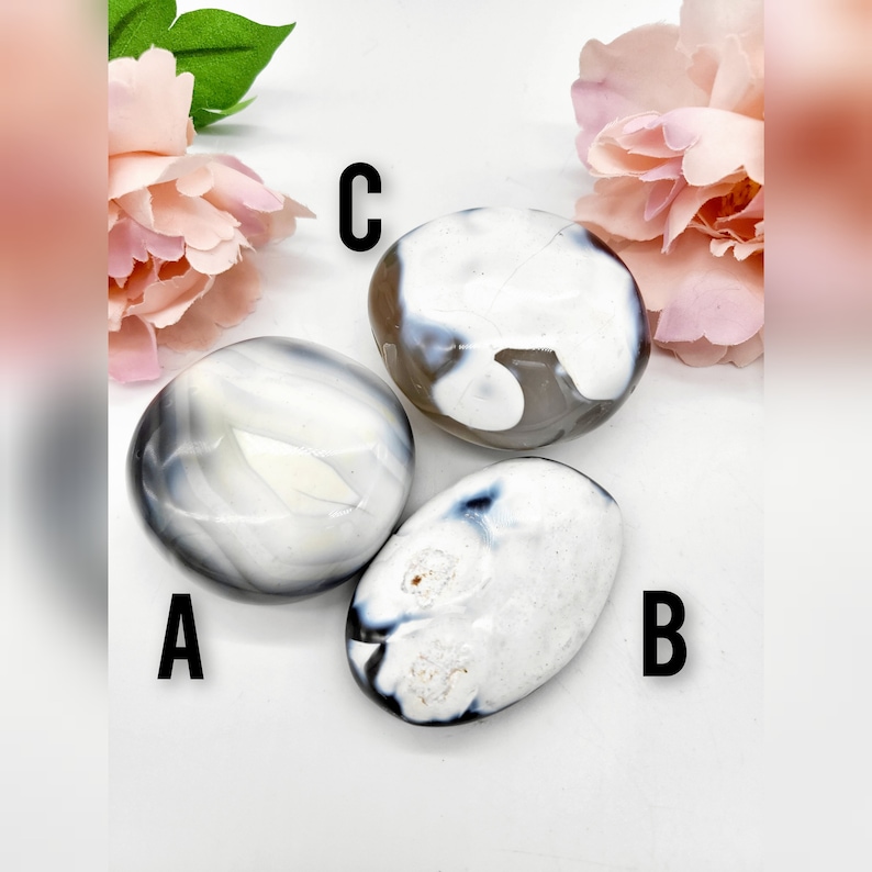 May include: Three white and gray agate stones with black banding. The stones are smooth and polished. The stones are labeled A, B, and C.