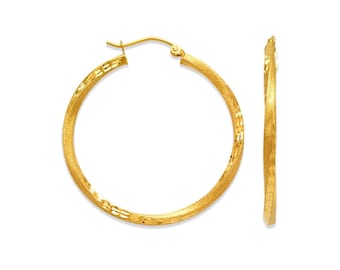May include: A pair of gold hoop earrings with a textured finish. The earrings are made of 14k gold and have a diameter of 1.5 inches.