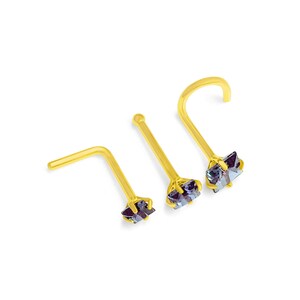 May include: Three gold nose rings with a small, square, iridescent gemstone. The rings are different sizes and are arranged in a row.