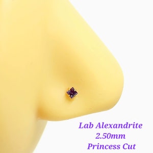 May include: A close-up of a purple lab-created alexandrite nose stud with a princess cut. The stud is 2.50mm in size and is set in gold.