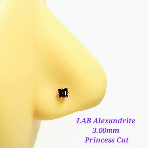 May include: A close-up of a purple lab-created alexandrite nose stud with a princess cut. The stone is 3.00mm in size.