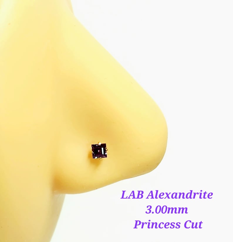 May include: A close-up of a purple lab-created alexandrite nose stud with a princess cut. The stone is 3.00mm in size.