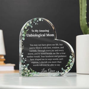 May include: A heart-shaped crystal plaque with a floral design and a message to an "Unbiological Mom". The message reads, "You may not have given me life, but you've filled it with love, wisdom, and warmth. Through every joy and every storm, you've stood beside me like a true mother would. Your kindness and guidance have shaped me in ways words can't express. I cherish you more than words will ever be able to say. Love, Grace."