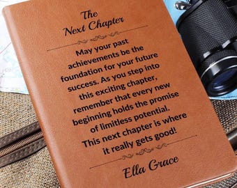 Puede incluir: Un diario de cuero marrón con el texto "The Next Chapter" y texto inspirador en negro. El diario está sobre un mapa. Una cámara es visible en el fondo.