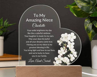 Puede incluir: Una placa de vidrio en forma de corazón con un diseño floral blanco y un mensaje que dice: "To My Amazing Niece Charlotte Your smile brightens my day like the a colorful rainbow. Your laughter is music to my ears. May your days be joyful and all your dreams come true. Having you as my niece is my greatest blessing in life. You bring light and love to our lives, and we're lucky to have you in our family. Love, Aunt Sarah"