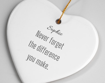 May include: A white heart-shaped ornament with the name "Sophie" and the message "Never forget the difference you make" printed in gray. A gold string is attached for hanging.