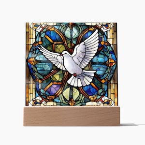 May include: A stained glass panel depicting a white dove with open wings, set against a backdrop of blues, greens, and yellows. The panel is mounted on a natural wood base, creating a decorative display.