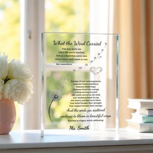 May include: A rectangular clear glass plaque featuring a printed dandelion graphic with seeds blowing in the wind. The text reads: What the Wind Carried, followed by a poem about seeds and legacy, ending with the name Ms. Smith in black script.