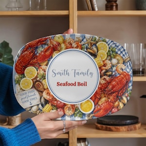 May include: Oval serving platter with a seafood boil design. The platter features illustrations of lobster, shrimp, corn, and lemons on a blue and white checkered background. Text includes "Smith Family Seafood Boil" and "Good Food Good Friends Good Times".