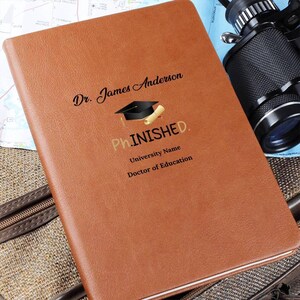 May include: A brown leather journal with the text "Dr. James Anderson" and "Ph.INISHED."  The journal also includes a graduation cap and diploma graphic. The text "University Name" and "Doctor of Education" is also included.