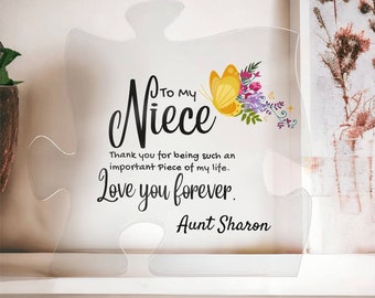 Puede incluir: Una pieza de rompecabezas de acrílico transparente con un diseño de mariposa y flores. El texto dice "To my Niece Thank you for being such an important Piece of my life. Love you forever. Aunt Sharon."