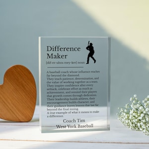 Könnte beinhalten: Ein klarer Acrylblock mit den Worten "Difference Maker" und einer Definition sowie einer Baseballspieler-Silhouette. Der Text beschreibt den Einfluss eines Baseballtrainers. Der Name des Trainers und das Team stehen unten.